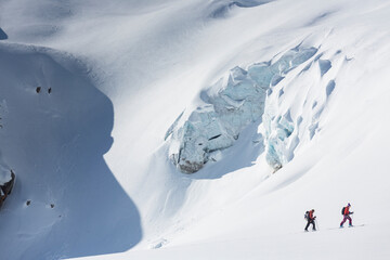 Backountry women skiers skinning up hill in the dramatic snowy mountains of the rugged Selkirks in British Columbia.