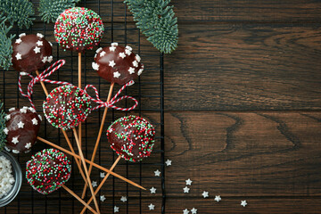 Marry Christmas sweet cake pops. Christmas dessert round brownie cake pops with stars topping on dark green background. Christmas food dessert concept and scene wide screen holiday border. Top view