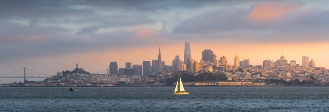 A sailboat in front of the San Francisco skyline, viewed from Sausalito at sunset.