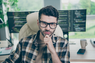 Photo of confident serious guy wear glasses arm hand chin programming modern device application indoors workstation workshop home