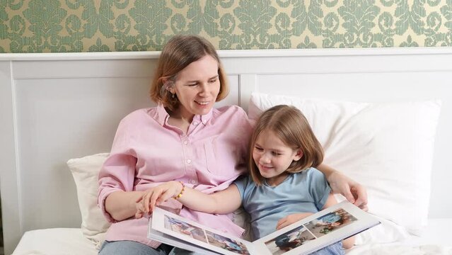 mom and daughter with a photobook with photos of a pregnancy family photo shoot