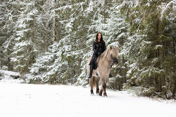 Woman dressed in black with light brown Icelandic horse.