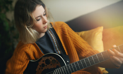 Teenage girl learning to play acoustic guitar.