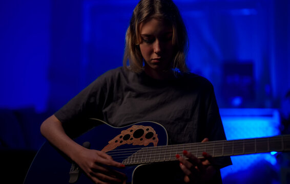Teenage girl learning to play acoustic guitar.
