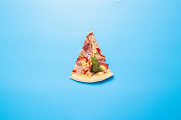 slice of hot fresh pizza lies on a blue background. Top view, flat lay