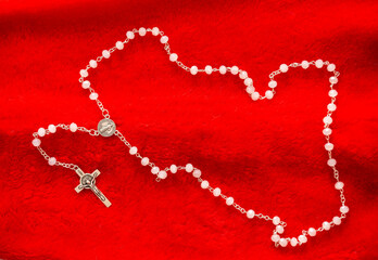 Catholic rosary and crucifix on red background