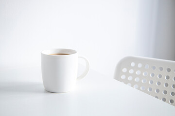 Coffee in a white cup on a white table under natural light.