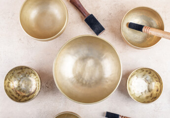 Tibetan singing bowls with stick used during mantra meditations on beige stone background, top...