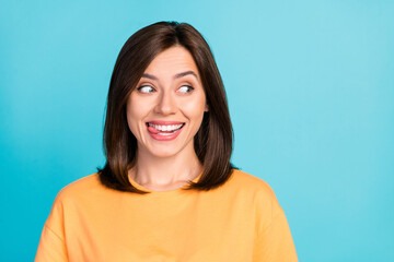 Photo of pretty positive person beaming smile bite tongue look empty space isolated on blue color background