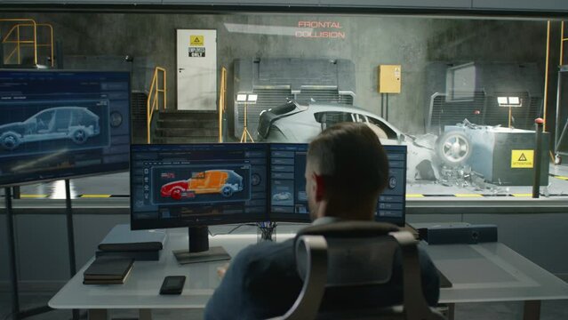 An engineer in a crash test lab uses a car crash test system to simulate a traffic accident, to obtain the safety parameters of an eco-friendly cutting edge electric vehicle being developed.