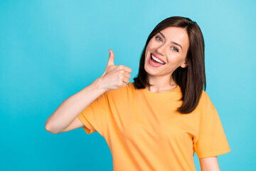 Portrait of glad pleasant cute woman with long hairstyle dressed yellow t-shirt showing thumb up...