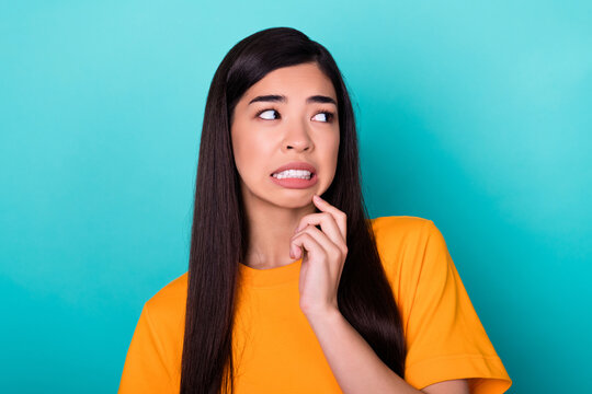 Photo of frightened nice girlish woman with long hairstyle wear yellow t-shirt look at empty space isolated on turquoise color background