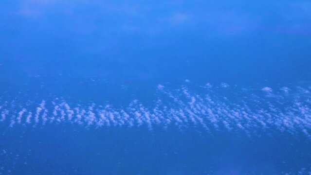 Cirrocumulus, granular cloudlets. Fleece clouds under the wing of an airplane. The flight takes place at an altitude of 11,000 meters