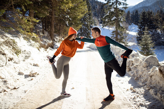 Female and male runner doing exercise at winter time