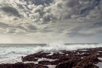 Powerful ocean wave hits rough stone coast of Aran Island, county Galway, Ireland. Rough nature scene. Water splash. Power of nature. Cloudy sky. Irish landscape. Popular tourist area