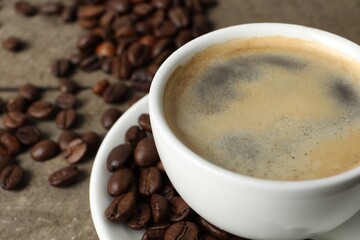 Cup of aromatic coffee and beans on wooden table, closeup. Space for text