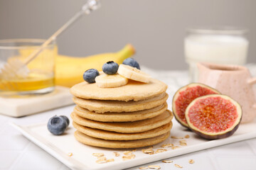 Tasty oatmeal pancakes on white tiled table, closeup