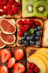 Tasty toasts with different spreads and fruits on wooden table, flat lay
