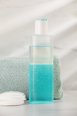 Obraz na płótnie Canvas Bottle of micellar water, towel and cotton pads on white table against marble background