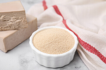 Granulated and compressed yeast on white marble table, closeup