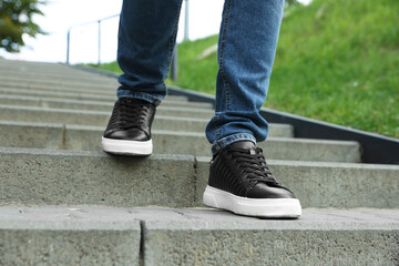 Man in stylish black sneakers walking down stairs, closeup