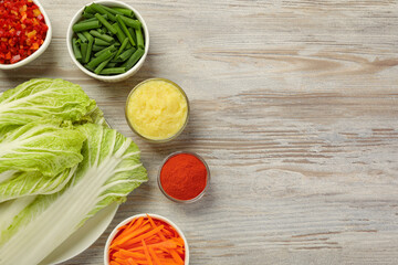 Fresh Chinese cabbages and other kimchi ingredients on wooden table, flat lay. Space for text
