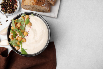 Flat lay composition of tasty chickpea soup in bowl, bread and spices served on light grey table. Space for text