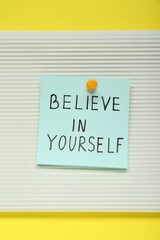 Note with phrase Believe In Yourself on yellow background, top view. Motivational quote