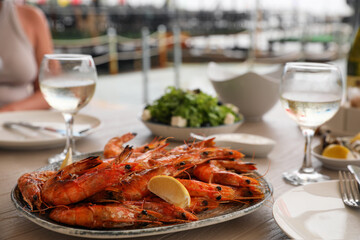 Plate of delicious cooked shrimps served with lemon and wine at table outdoors