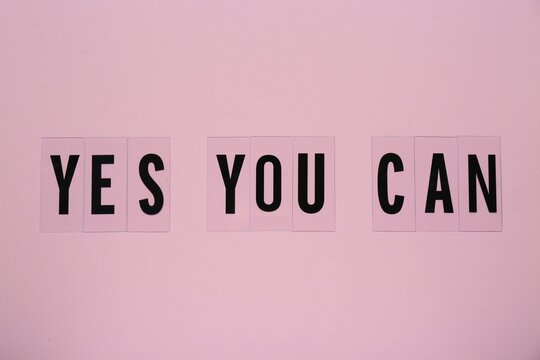 Phrase Yes You Can of plastic letters on pink background, top view. Motivational quote