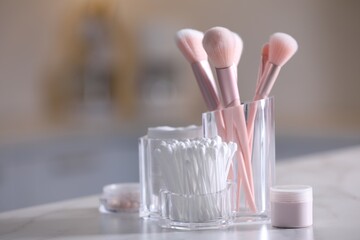 Cotton buds, pads and makeup brushes in transparent holders on light table