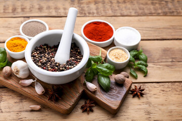 Mortar with pestle and different spices on wooden table