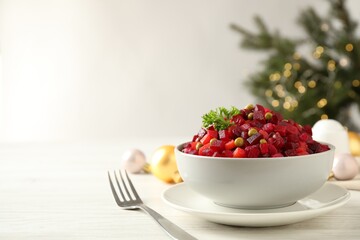 Traditional Russian salad vinaigrette served on white wooden table. Space for text