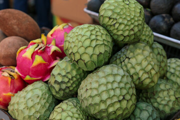 Fototapeta premium Cherimoya and dragon fruit at market, closeup