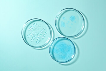 Petri dishes with liquids on turquoise background, flat lay