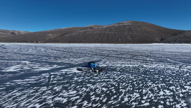 Aerial mountain lake ice fishing Utah circle 3. Outdoor winter recreation and sport. Mountain alpine lake. Social activity with family and friends. Ice forms for safety. Tents and heaters for comfort.