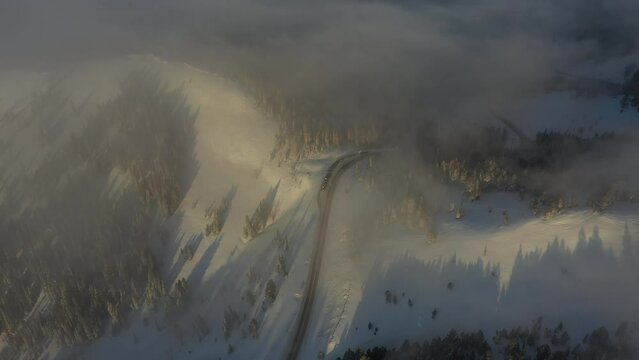 Aerial View of Misty Sunny Morning Above Snow Capped Mountain Hills and Peaks. Flying Above Hayden Pass, Colorado USA at Sunrise