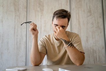 one man sitting at the office at work having eye strain pain eyestrain