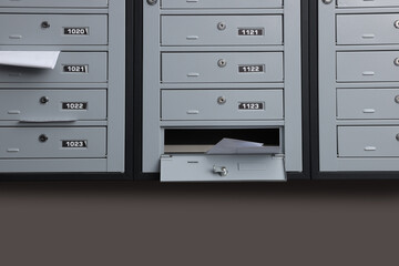 Grey metal mailboxes with receipts and envelopes indoors