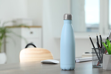 Stylish thermo bottle on wooden table at home. Space for text