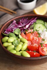 Poke bowl with salmon, edamame beans and vegetables on wooden table, closeup
