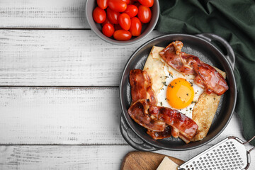 Delicious crepe with egg and bacon in dish on white wooden table, flat lay with space for text. Breton galette