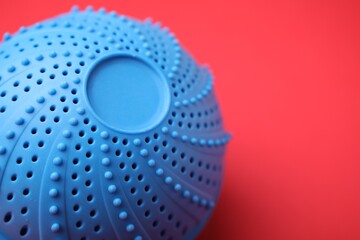 Laundry dryer ball on red background, closeup. Space for text