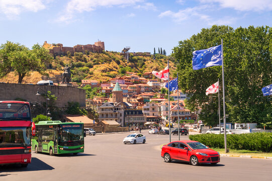 Traffic on a roundabout on Noe Jordania Bank street in foreground and dome of St. Gevorg Cathedral among streets of Dzveli Old Tbilisi neighborhood of the capital of Georgia Tbilisi city climbing up