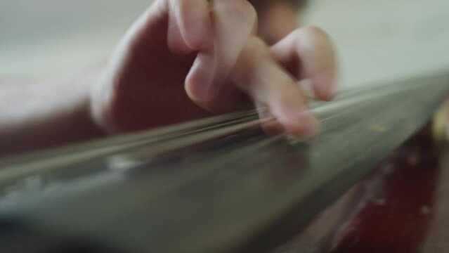 Low angle rack focus shot of jazzman plucking strings of double bass while playing music