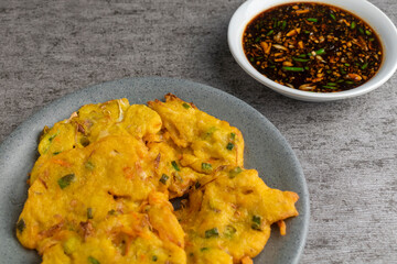 bakwan is vegetable fritter from Indonesia. made from mixed vegetable and flour fried in cooking oil. served with dark spicy sauce