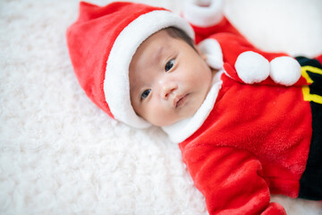 クリスマスにサンタの服を着る生後２か月の赤ちゃん
