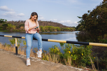 Fototapeta premium young woman with cell phone by the lake