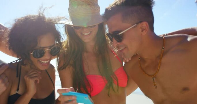 Friends, phone and selfie at a beach for travel, relax and fun with group bonding in summer. Happy, people and smile for picture on smartphone on ocean trip by women, men and laughing in Mexico