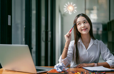 Idea light bulbs with young girl in a thoughtful face sitting at co-workspace.